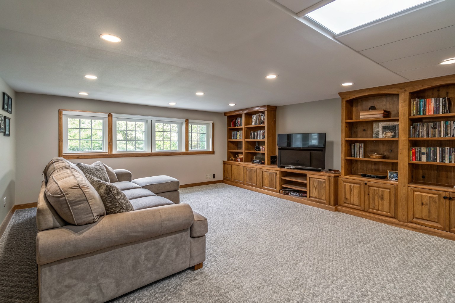 A dry finished basement family room with a sectional sofa, built-in bookshelves and small high windows